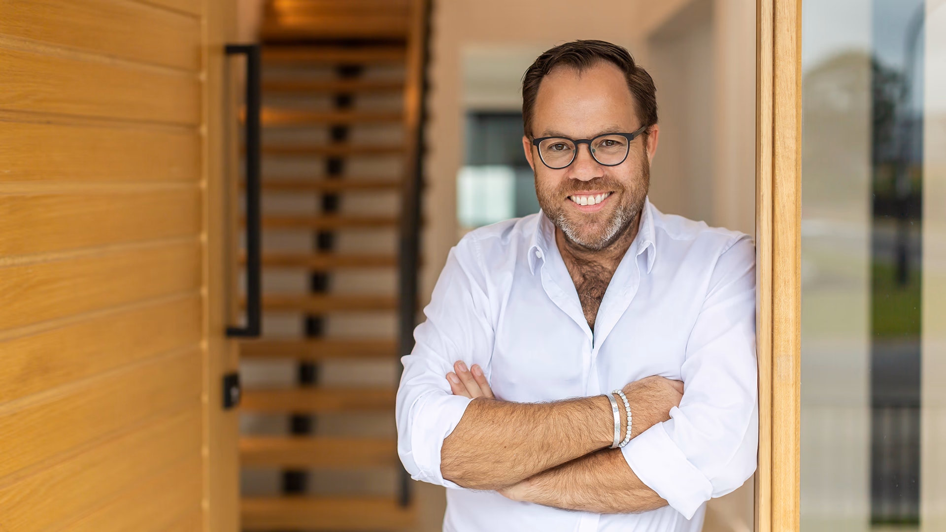 James Treble smiling in a white shirt with his arms crossed