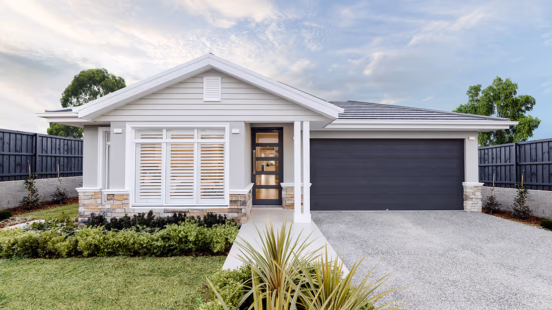 Modern single-story house with light gray siding, large front windows with white shutters, stone accents, a dark double garage door, and a neat front yard with green shrubs and a small palm.
